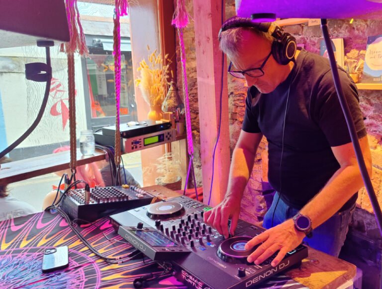 Cosmic Turtle DJing at Hairy Barista, Totnes under UV lighting, 2026