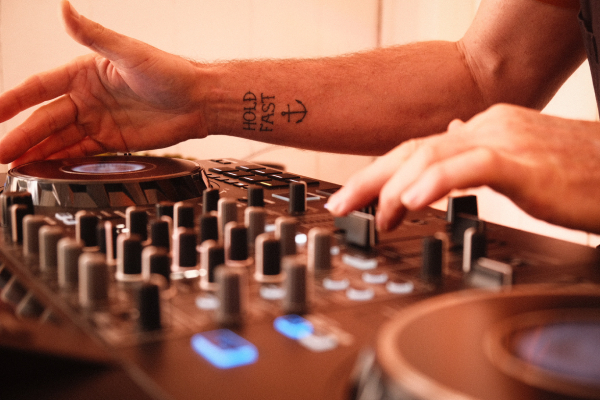 Cosmic Turtle DJing close up with tattoo "Hold Fast"